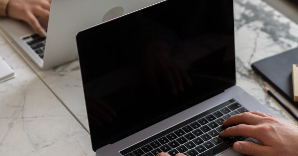 Two people working on laptops at a shared desk
